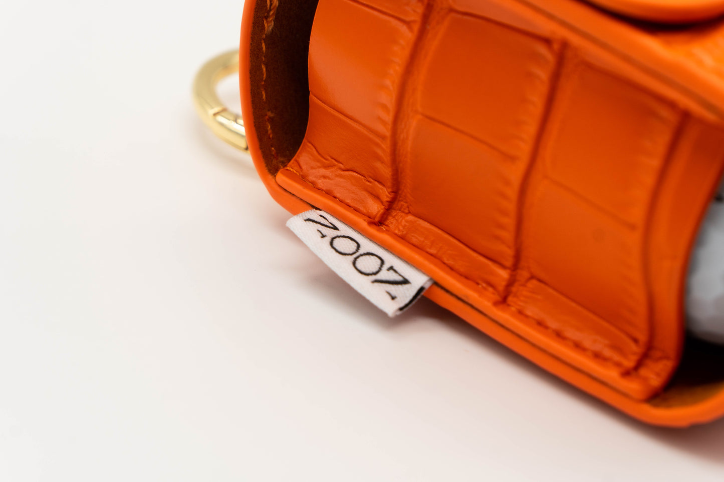Noon brand logo stitched onto the side of a orange golf ball pouch