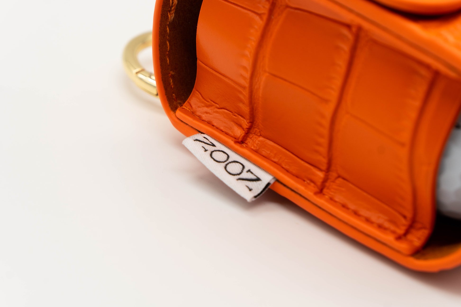 Noon brand logo stitched onto the side of a orange golf ball pouch