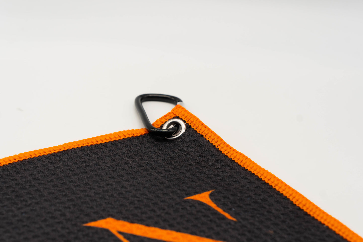 Golf towel with black carabiner attached at the side of the towel