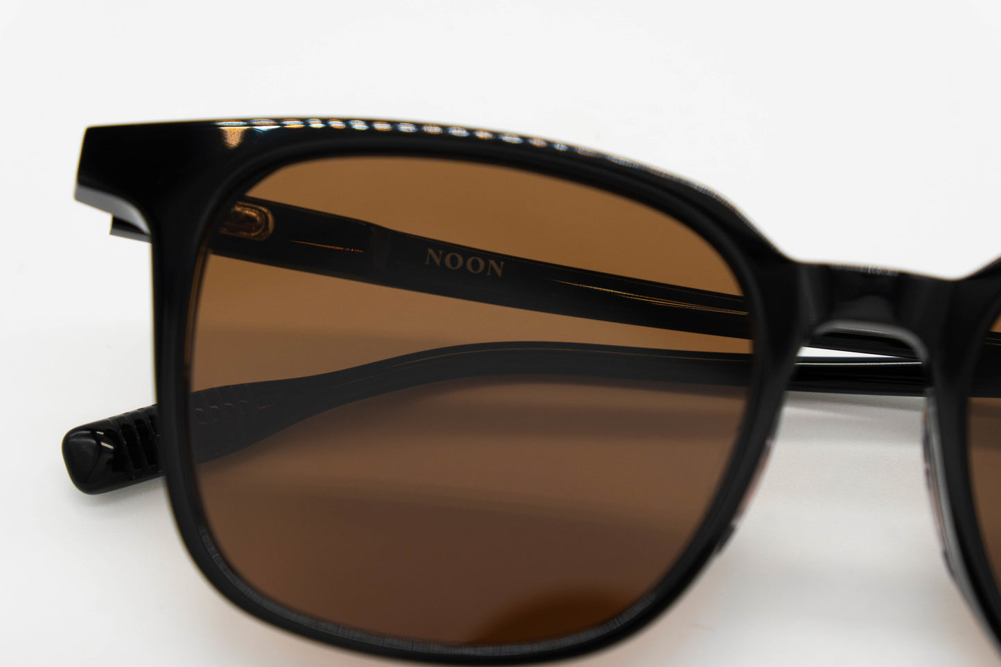 Close up details of Paxton sunglasses in black against a white background